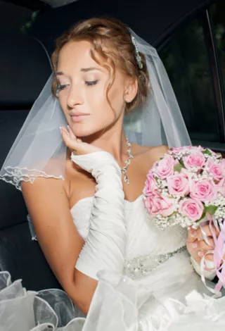 Bride sitting in a limo holding flowers